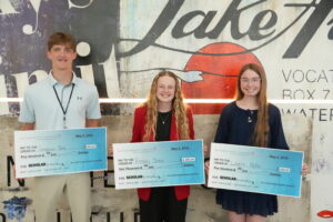 Three scholarship winners hold big checks